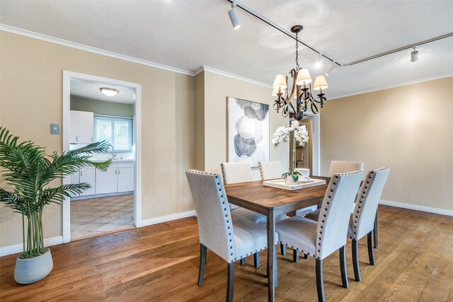 430 Mayrant Dr, Dallas, TX 75224 - dining area with rail lighting, wood finished floors, a chandelier, baseboards, and crown molding