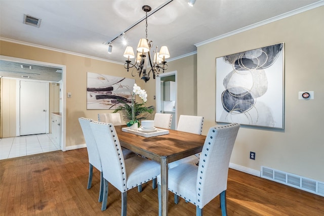 430 Mayrant Dr, Dallas, TX 75224 - dining room with rail lighting, a chandelier, baseboards, ornamental molding, and wood finished floors