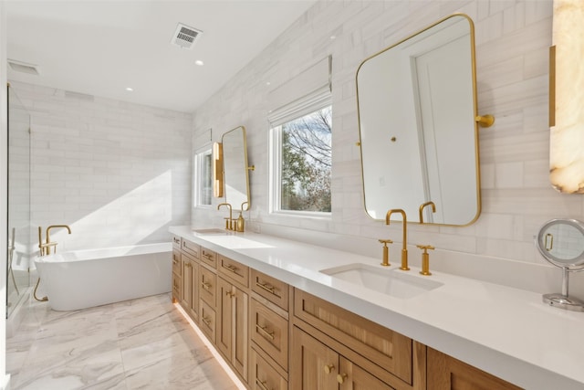 bathroom with a sink, visible vents, tile walls, marble finish floor, and a soaking tub