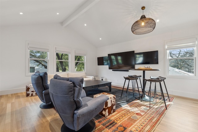 living area featuring lofted ceiling with beams, light wood-style floors, and a healthy amount of sunlight