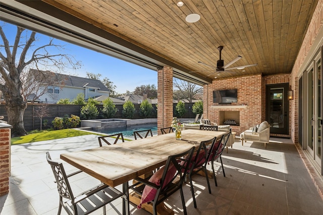 view of patio / terrace with an outdoor brick fireplace, outdoor dining area, a fenced backyard, and a pool with connected hot tub