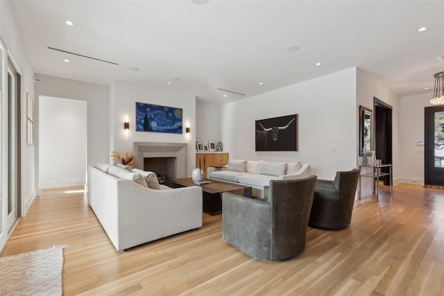 living room featuring baseboards, recessed lighting, a fireplace, and light wood-style floors