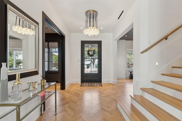 foyer featuring baseboards, stairway, plenty of natural light, and an inviting chandelier