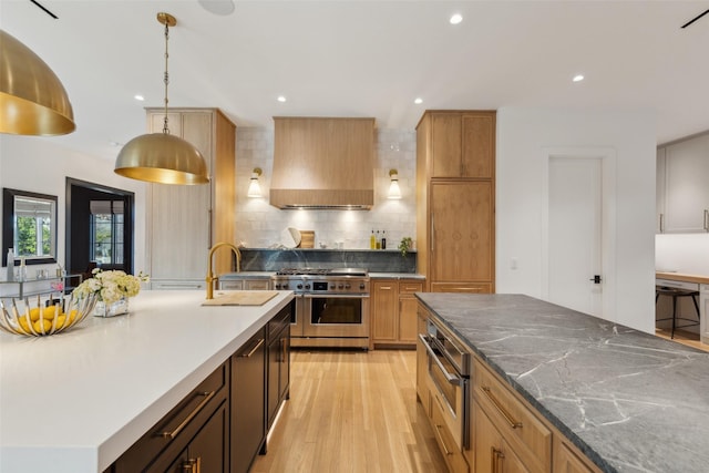 kitchen with range with two ovens, a center island, hanging light fixtures, light wood-style floors, and premium range hood