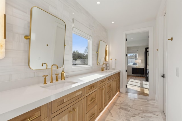 full bath featuring ensuite bathroom, marble finish floor, a sink, and a wealth of natural light