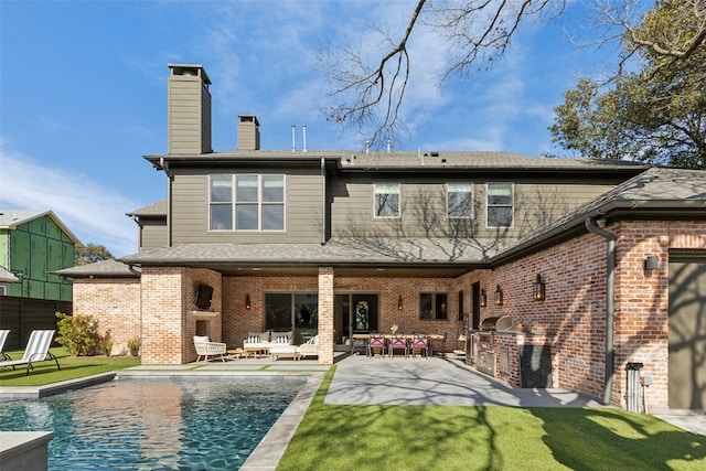 back of house with brick siding, a fireplace, fence, exterior kitchen, and a patio area