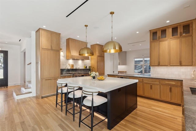 kitchen featuring light countertops, hanging light fixtures, a kitchen island, a kitchen breakfast bar, and extractor fan