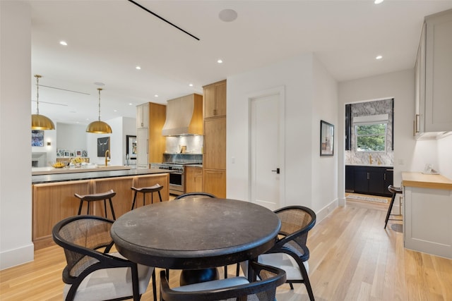 dining room featuring baseboards, light wood-style flooring, and recessed lighting