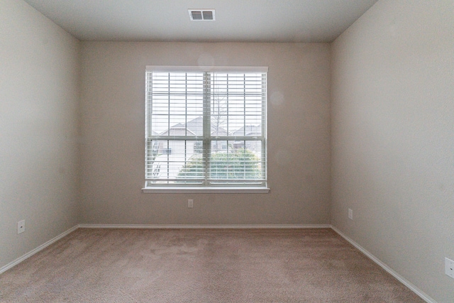 unfurnished room featuring baseboards, visible vents, and light colored carpet