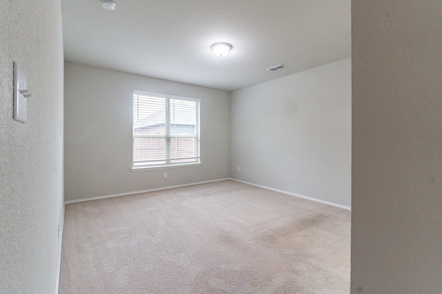 empty room with visible vents, light carpet, and baseboards