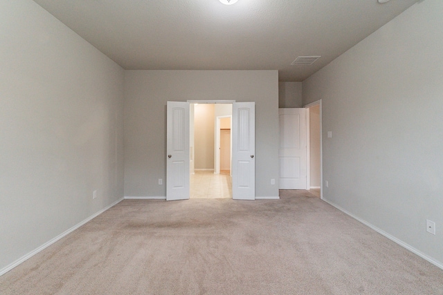 unfurnished bedroom with light carpet, visible vents, and baseboards