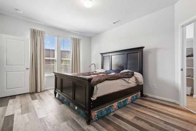 bedroom featuring light wood-style flooring, visible vents, and baseboards