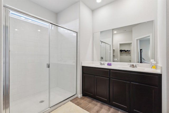 full bathroom with double vanity, a stall shower, wood tiled floor, and a sink