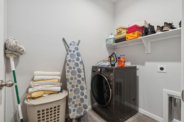 laundry room featuring laundry area, baseboards, wood finished floors, and washer / dryer