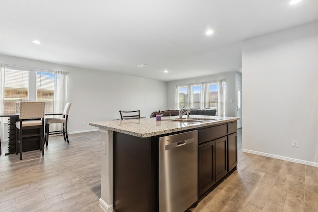 kitchen with a sink, light wood finished floors, a kitchen island with sink, and stainless steel dishwasher