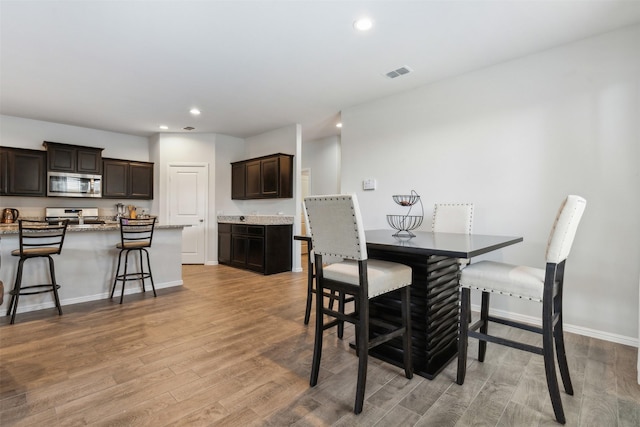 dining room featuring light wood finished floors, baseboards, visible vents, and recessed lighting