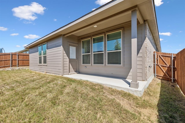 rear view of house featuring fence private yard, a patio, and a lawn