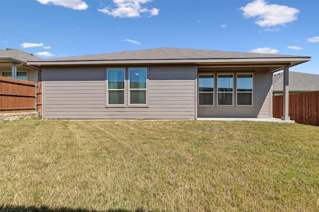 rear view of property with fence and a lawn