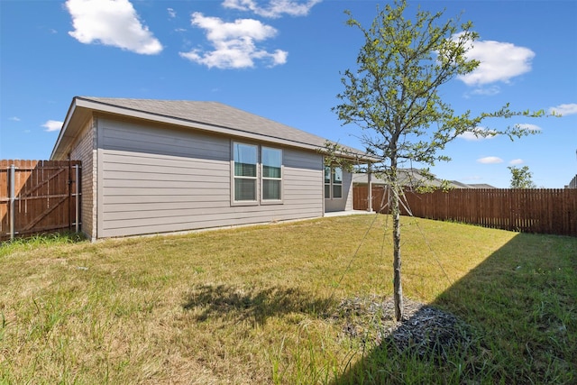 back of house with a yard and a fenced backyard