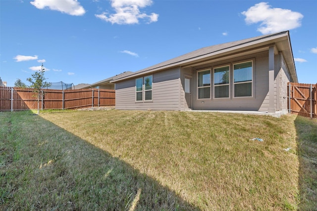 back of property with a fenced backyard and a yard