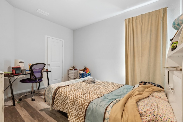 bedroom with visible vents, baseboards, and wood finished floors