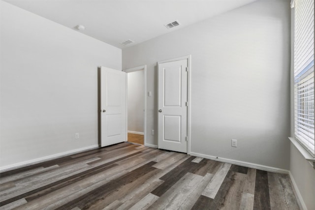 unfurnished bedroom featuring baseboards, visible vents, and dark wood finished floors