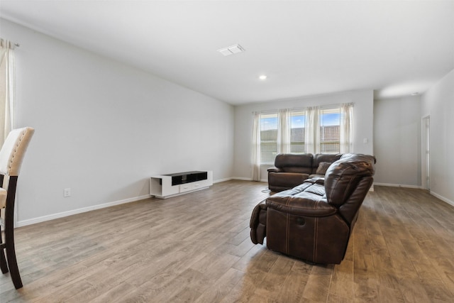 living room featuring recessed lighting, light wood-type flooring, visible vents, and baseboards