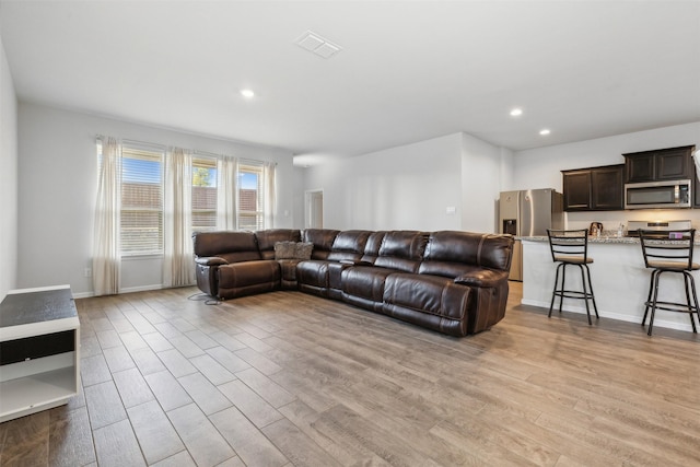 living area featuring baseboards, light wood finished floors, visible vents, and recessed lighting