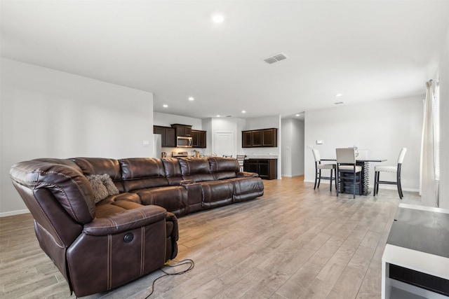 living room featuring light wood-style floors, recessed lighting, visible vents, and baseboards