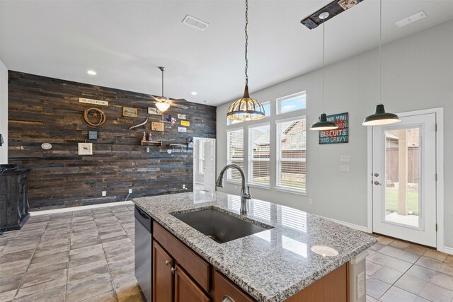 kitchen with dishwasher, wood walls, a sink, and visible vents