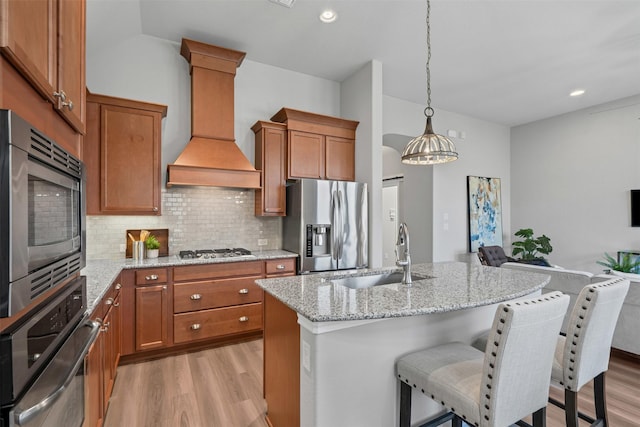 813 Louisville Rd, Aubrey, TX 76227 - kitchen with appliances with stainless steel finishes, a sink, light wood finished floors, custom exhaust hood, and brown cabinetry