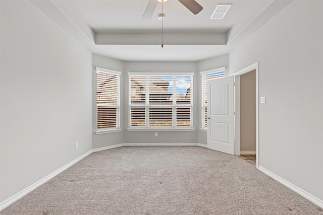 empty room featuring a raised ceiling, visible vents, and baseboards