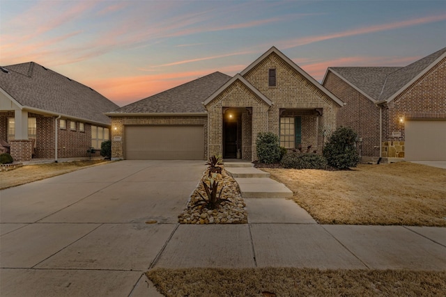 view of front of home featuring a shingled roof, concrete driveway, brick siding, and a garage