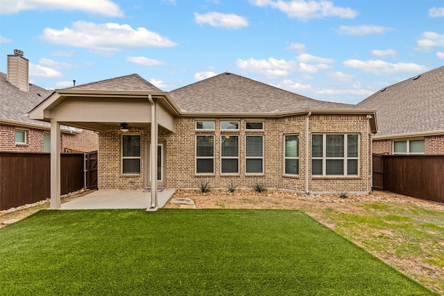 back of property with brick siding, a yard, roof with shingles, a patio area, and ceiling fan