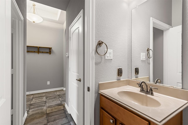 bathroom with a textured wall, vanity, and baseboards