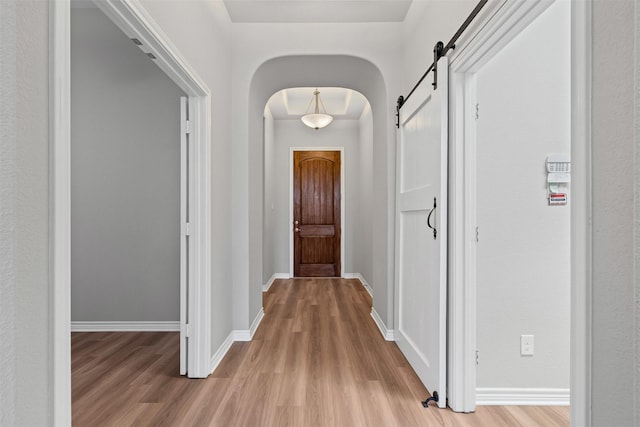 813 Louisville Rd, Aubrey, TX 76227 - hall featuring a barn door, light wood-style floors, arched walkways, and baseboards