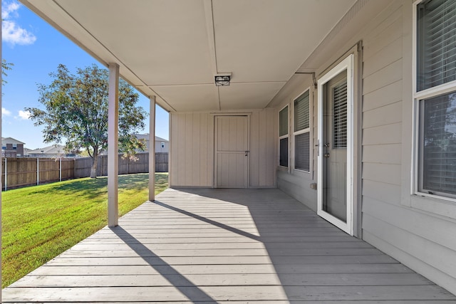 wooden terrace featuring a yard and fence