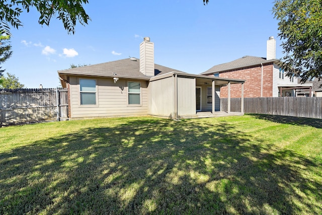 back of house with a patio area, a fenced backyard, a lawn, and a chimney