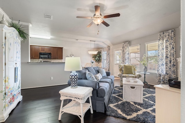 living area with visible vents, dark wood finished floors, baseboards, and ceiling fan