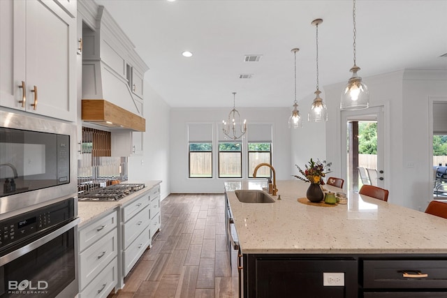 kitchen with a kitchen island with sink, a sink, visible vents, white cabinetry, and appliances with stainless steel finishes