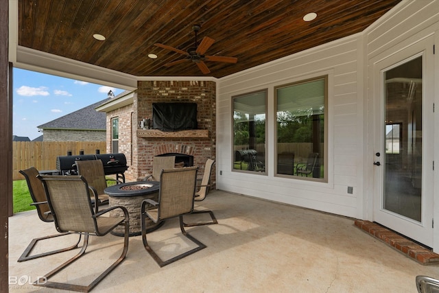 view of patio / terrace with an outdoor brick fireplace, fence, and ceiling fan