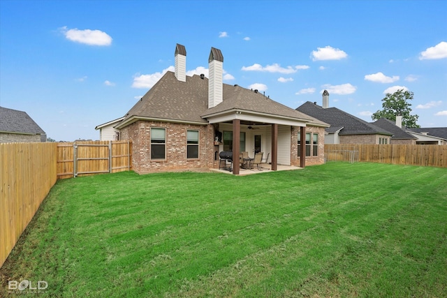 rear view of property featuring brick siding, a yard, a patio, a gate, and a fenced backyard