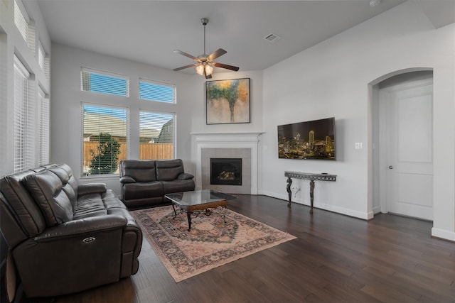 living area with arched walkways, dark wood-type flooring, a tile fireplace, and visible vents