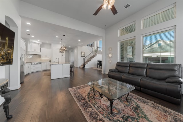 living room featuring stairs, dark wood-style floors, visible vents, and baseboards