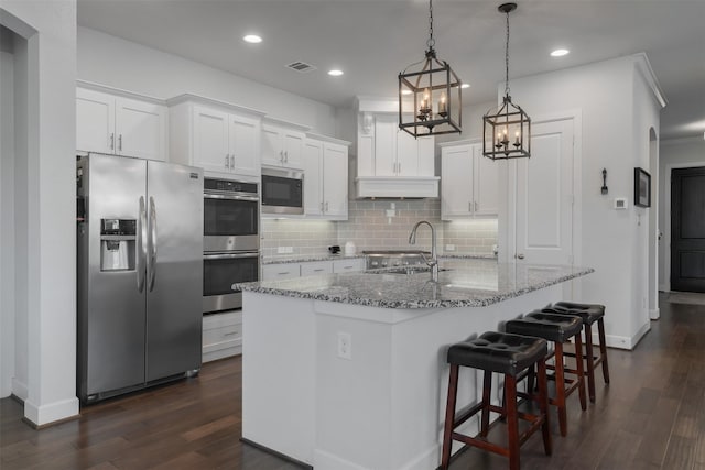 kitchen with a kitchen island with sink, stainless steel appliances, visible vents, and white cabinets