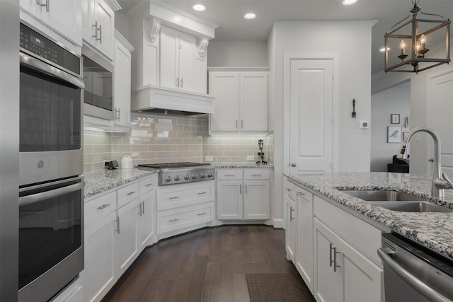 kitchen with hanging light fixtures, appliances with stainless steel finishes, a sink, and white cabinetry