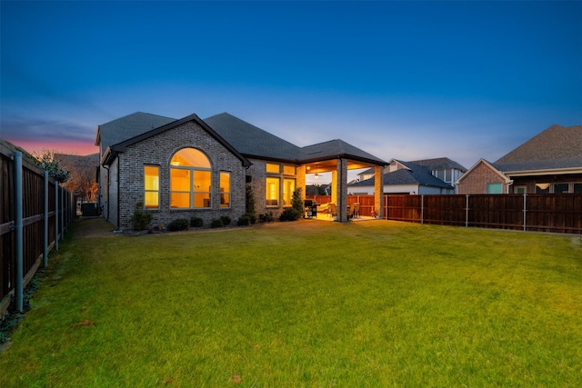 back of house with a yard, a fenced backyard, and brick siding