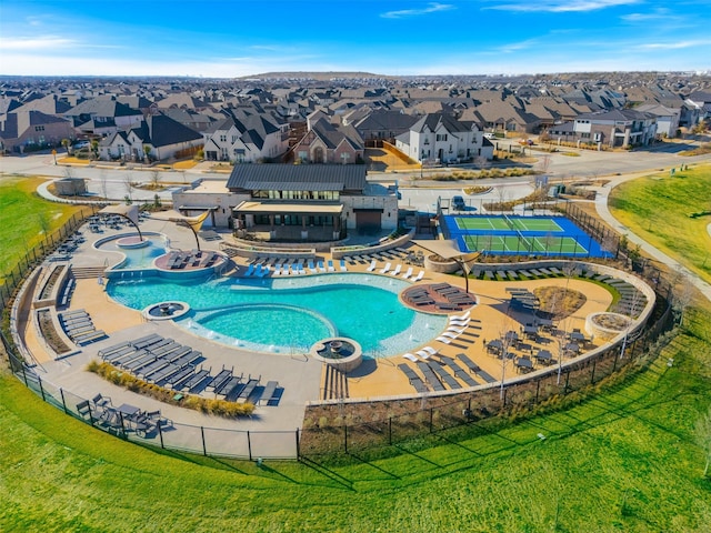 community pool with a residential view, fence, a hot tub, and a lawn