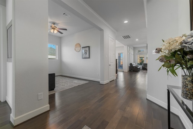 interior space with dark wood-style floors, crown molding, visible vents, and baseboards