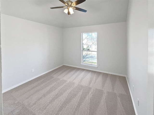 carpeted empty room with baseboards and a ceiling fan